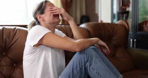 Una mujer sentada en el sofá está llorando amargamente, un primer plano, una cámara lenta. Concepto sufrimiento emocional, dolor - Metraje, vídeo