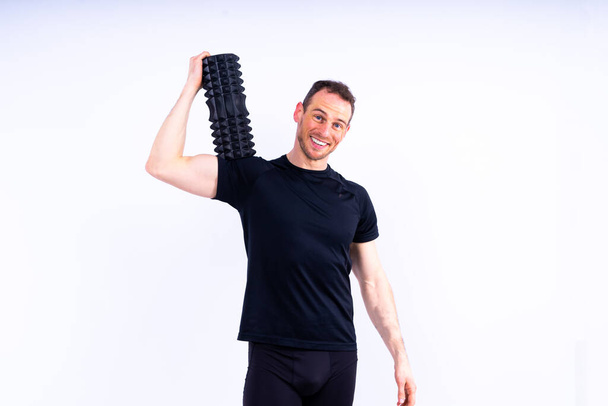 運動後の筋肉痛を和らげるために発泡ローラーを使用する運動男性. - 写真・画像