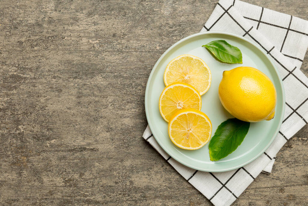 Frissen vágott citrom és egész citrom kerek tányéron, színes háttérrel. Élelmiszer és ital összetevők elkészítése. egészséges étkezési téma felső nézet vith másolás hely. - Fotó, kép
