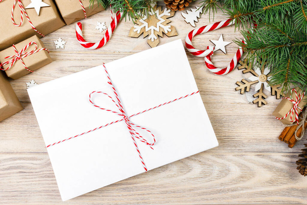 Посилка в конверті з ялинковими гілками та різдвяними прикрасами на дерев'яному тлі
. - Фото, зображення