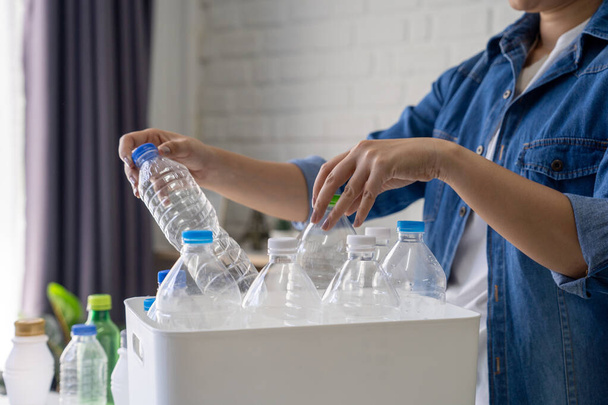 Uma mulher recolhendo e separando garrafas de plástico de lixo reciclável em uma lixeira em casa. - Foto, Imagem