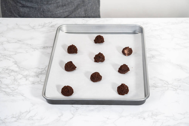 Scooping cookie dough with a small dough scoop into a baking sheet lined with parchment paper to bake peppermint white chocolate cookies. - Φωτογραφία, εικόνα