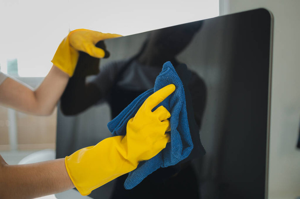 Cleaner is working, Wear rubber gloves and an apron to work, Cleaning staff wiping down office equipment, Wipe the monitor clean with a towel and sanitizer, cleaning idea. - Photo, Image