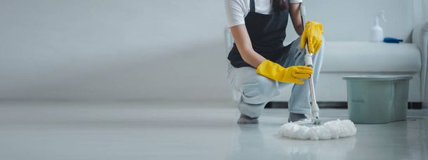 Takarító személyzet felmosó padló otthon Viseljen kötényt és gumikesztyűt, hogy megvédje a tisztító vegyi anyagok. Használj felmosót a padló megtisztításához. tartsa tiszta belül a házban, hogy megakadályozzák a baktériumok tisztítása ötletek. - Fotó, kép