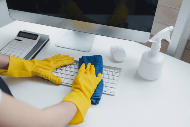 Cleaning staff wiping down office equipment, Wipe the keyboard clean with a towel and disinfectant. Wear rubber gloves when working with cleaning chemicals, cleaning idea. - Photo, Image