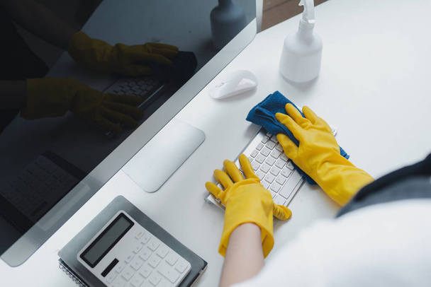 オフィス機器を掃除するスタッフは,タオルと消毒剤でキーボードをきれいに拭きます. クリーニングの化学薬品,クリーニングの考えと働くときゴム製手袋を身に着けて下さい. - 写真・画像