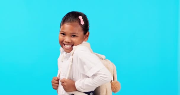 Sourire, visage et fille enfant en studio avec sac à dos pour la rentrée scolaire, excité et doux sur fond bleu. Heureux, portrait et enfant féminin gai sur la maternelle, adorable et posant isolé. - Séquence, vidéo
