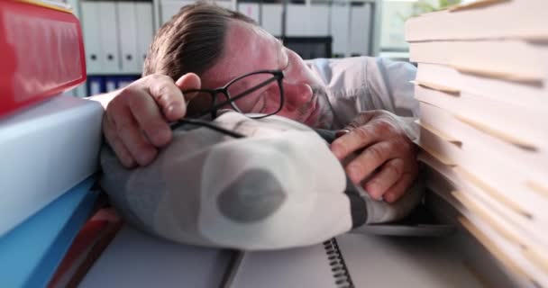 Zakenman met bril in de hand slapen op kussen tussen documenten 4k film slow motion. Werkaholia-concept - Video