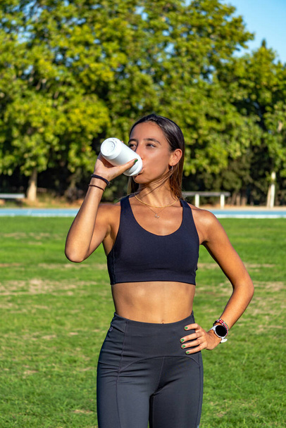 Beautiful young slim runner girl, drinking and hydrating by suck - Photo, Image