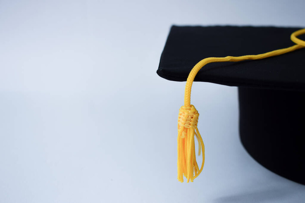 Sombrero de graduación negro de primer plano y borla amarilla aislados sobre fondo blanco - Foto, imagen