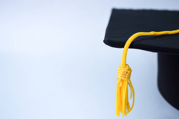Sombrero de graduación negro de primer plano y borla amarilla aislados sobre fondo blanco - Foto, Imagen