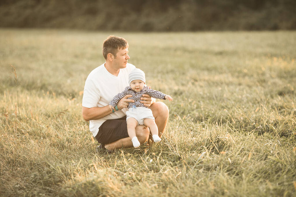Un père profite d'un moment ludique dans un champ d'été, comme le père jeter bébé fils. La famille joyeuse regarde avec joie et amour - Photo, image