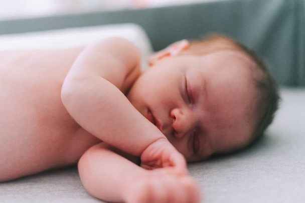 Portret van een pasgeboren baby van een week oud die op een babybedje slaapt - Foto, afbeelding