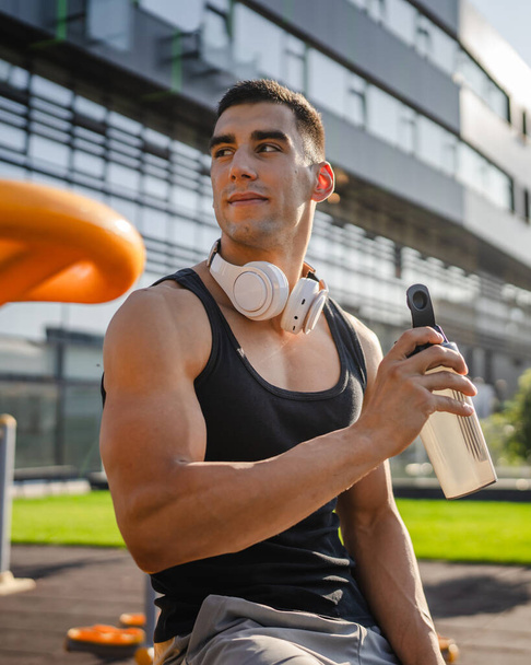 Один кавказский мужчина молодой спортсмен во время тренировки на открытом воздухе в парке держит в руке шейкер дополнения счастливо уверенно сильное пространство для копирования - Фото, изображение