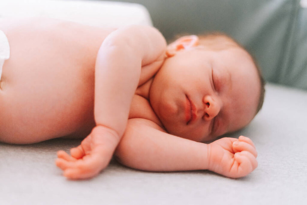 Portré egy egyhetes újszülött babáról, aki egy kiságyon alszik. - Fotó, kép