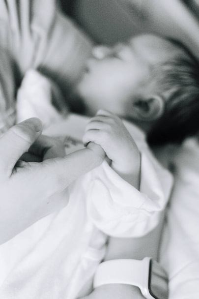 Detalle de una mano recién nacida de un día sosteniendo el dedo de su padre - Foto, imagen