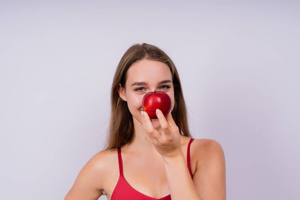 Πρωινό πρωινό. Γυναίκα με υγιή δόντια κρατώντας μήλα σε ένα γκρι απομονωμένο φόντο. - Φωτογραφία, εικόνα