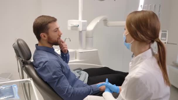 Egy boldog ember portréja, aki a fogorvosi székben ül a modern klinikán és mosolyog. Professzionális fogorvossal végzett fogászati kezelést élvező beteg - Felvétel, videó