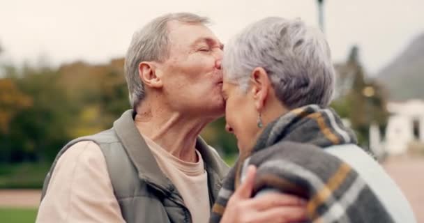 Forehead, kiss and senior couple in a park with love, happy and conversation with romantic bonding. Kissing, old people and elderly man embrace woman with care, romance or soulmate connection outdoor. - Footage, Video