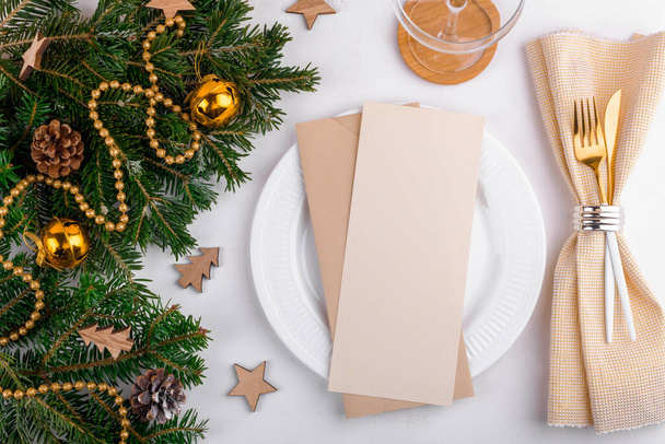 Pionowe menu świąteczne makieta ze złotym świątecznym nakryciem stołu z świąteczną dekoracją na naturalnej gałązce świeżej jodły. Menu świąteczne lub zaproszenie 4x9 stosunek. Płaskie ułożenie, widok z góry - Zdjęcie, obraz