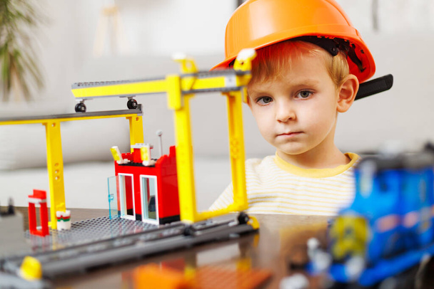 Child boy in helmet playing and building with colorful plastic bricks at the table. Early learning and development - Photo, Image