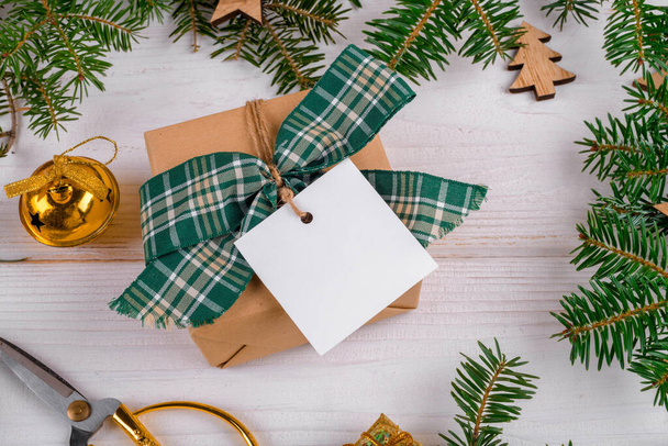 Kerst vierkante gift tag mockup met ambachtelijke verpakt geschenkdoos op een witte achtergrond met rand van natuurlijke sparren takken, close-up, kerstversiering, bovenaanzicht. Vakantie wintercompositie, - Foto, afbeelding