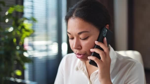 Siyahi akıllı telefonları tutan ve uzaktan sorunları çözerken konuşan ciddi sekreterlere yakın durun. Çekici Afrikalı Amerikalı bayan ofiste müşteriyle tartışıyor ve onunla hemfikir.. - Video, Çekim