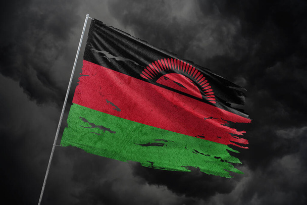 Malawi zerrissene Flagge vor dunklem Himmel. - Foto, Bild