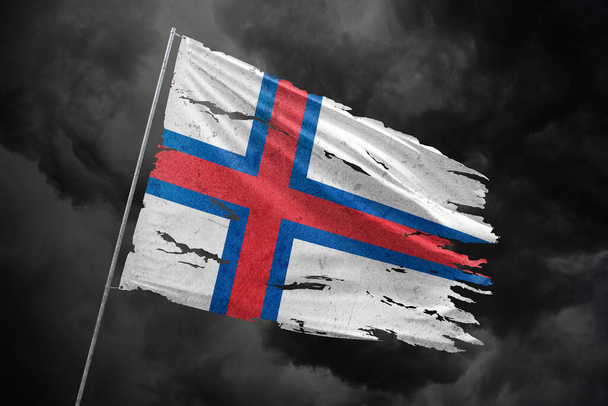 Färöer-Inseln zerrissene Flagge vor dunklem Himmel. - Foto, Bild
