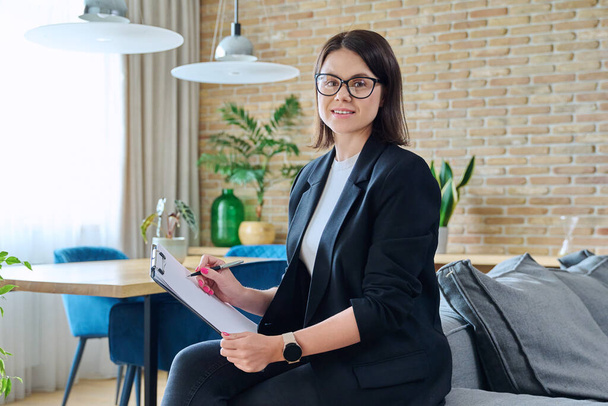 Portrait of young female psychologist with clipboard in modern office. Confident friendly woman professional mental therapist. Therapy service, psychology, psychotherapy, advice, support, treatment - Foto, Imagem