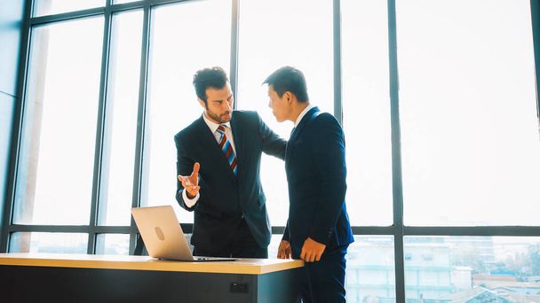 Two business people talk project strategy at office meeting room. Businessman discuss project planning with colleague at modern workplace while having conversation and advice on financial report. Jivy - Photo, Image