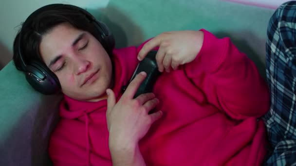 muotokuva nuori kaveri gamer huoneessa nukahtaa pelattuaan PS5 kanssa peliohjain. Laadukas 4k kuvamateriaalia - Materiaali, video