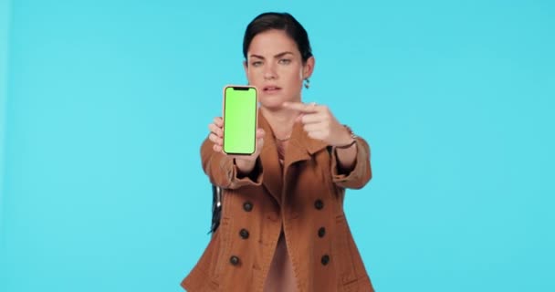 Zöld képernyős telefon, hüvelykujj le, és a nő rámutatnak a rossz mockup design, márka hiba és egyet nem értés a stúdió térben. Mobil logó, nincs szavazat és portré személy negatív véleményt kék háttér. - Felvétel, videó