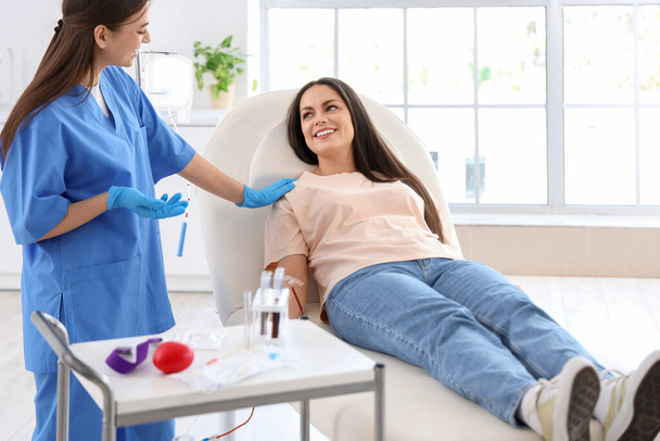 Donante de sangre femenina hablando con enfermera en clínica - Foto, imagen