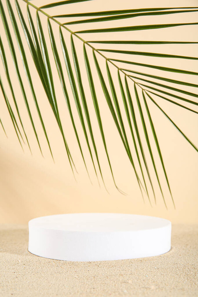 Decoratieve gips podium met palmblad op zand tegen beige achtergrond - Foto, afbeelding