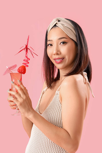 Όμορφη Ασιάτισσα με μαγιό και κοκτέιλ φράουλας σε ροζ φόντο - Φωτογραφία, εικόνα