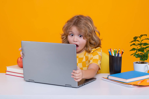 Excited school child using laptop computer. Back to school. Portrait of cute child school boy, isolated on yellow studio background. Education kids concept. Clever kid with school supplies - Photo, Image