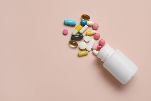 Jar with different scattered pills on beige background - Photo, Image