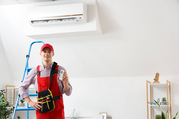 Mies teknikko ilmastointilaite kaukosäädin huoneessa - Valokuva, kuva
