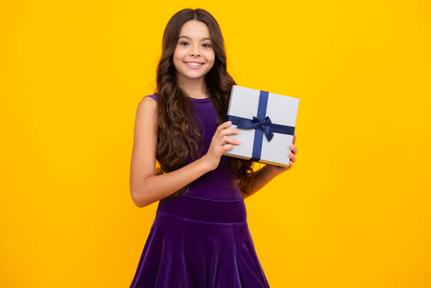 Kind Teenager Mädchen 12-14 Jahre alt mit Geschenk auf isoliertem Hintergrund. Geburtstag, Urlaubskonzept. Teenager halten Geschenkbox. Glückliches Mädchengesicht, positive und lächelnde Emotionen - Foto, Bild