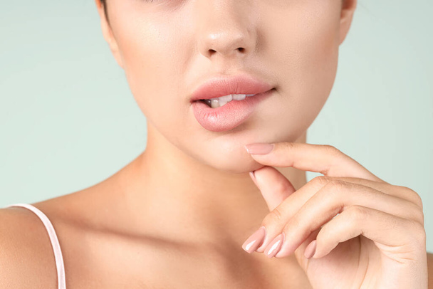 Gedachte jonge vrouw met mooie lippen op groene achtergrond, close-up - Foto, afbeelding