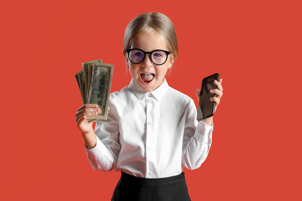 Симпатична маленька секретарка з мобільним телефоном і грошима на червоному тлі - Фото, зображення