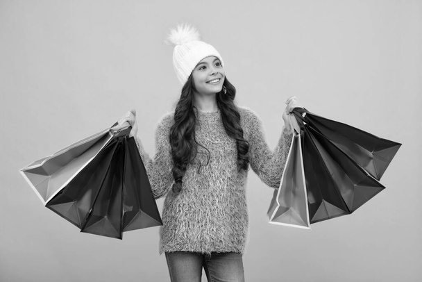 Stylish teen girl in autumn warm hat with shopping sale bags. Kid holding purchases. Happy girl face, positive and smiling emotions - Photo, Image