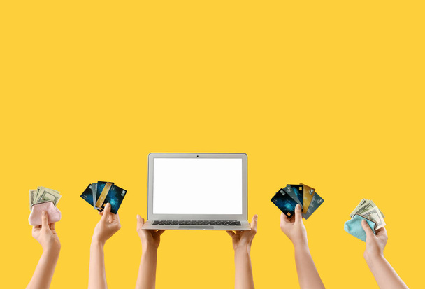 Femmes avec ordinateur portable vierge, argent et cartes de crédit sur fond jaune - Photo, image
