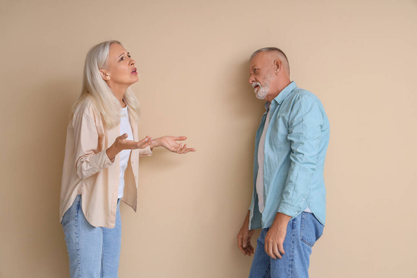 Volwassen echtpaar ruziënd over beige achtergrond. Scheidingsconcept - Foto, afbeelding