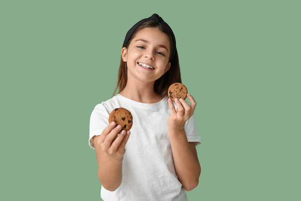 Little girl holding sweet chocolate cookies on green background - Photo, Image