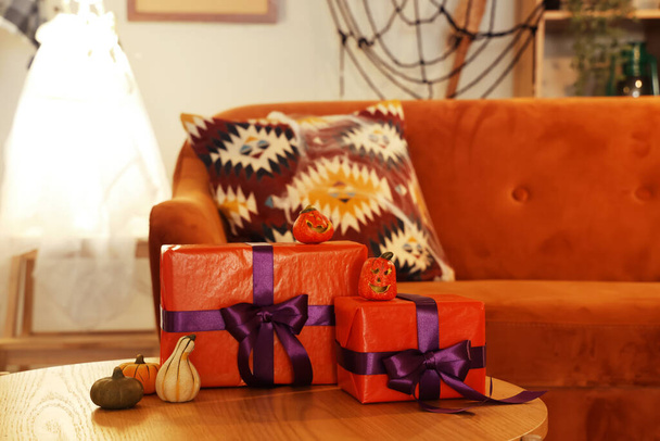 Coffee table with Halloween gift boxes and pumpkins in living room, closeup - Photo, Image