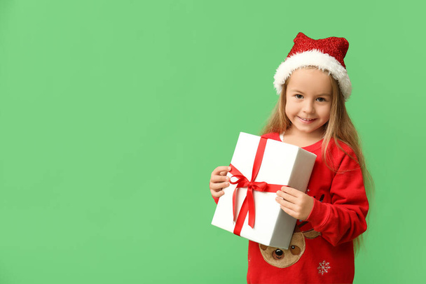 Милая маленькая девочка в костюме эльфа с подарочной коробкой на зеленом фоне - Фото, изображение