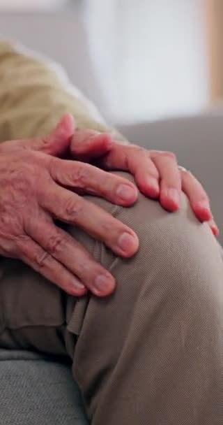 Knie pijn, stress en handen van senior man op de bank met artritis, probleem of osteoporose thuis close-up. Zoom, letsel en oudere man met been massage in een woonkamer met artrose probleem. - Video