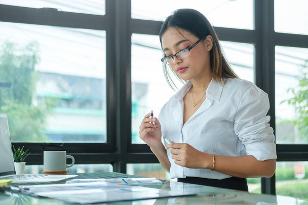 Portrait of businesswoman sitting at office desk and checking documents. - Foto, Imagen